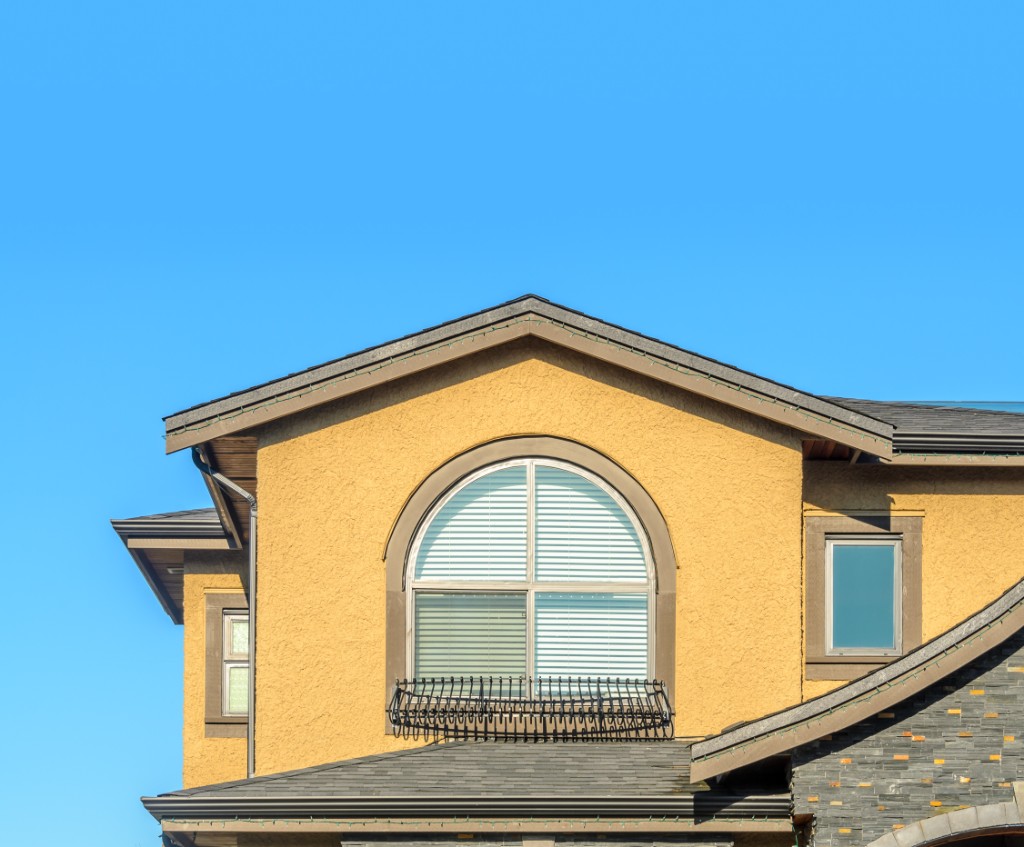 Arched feature window in a gable with stone and stucco exterior