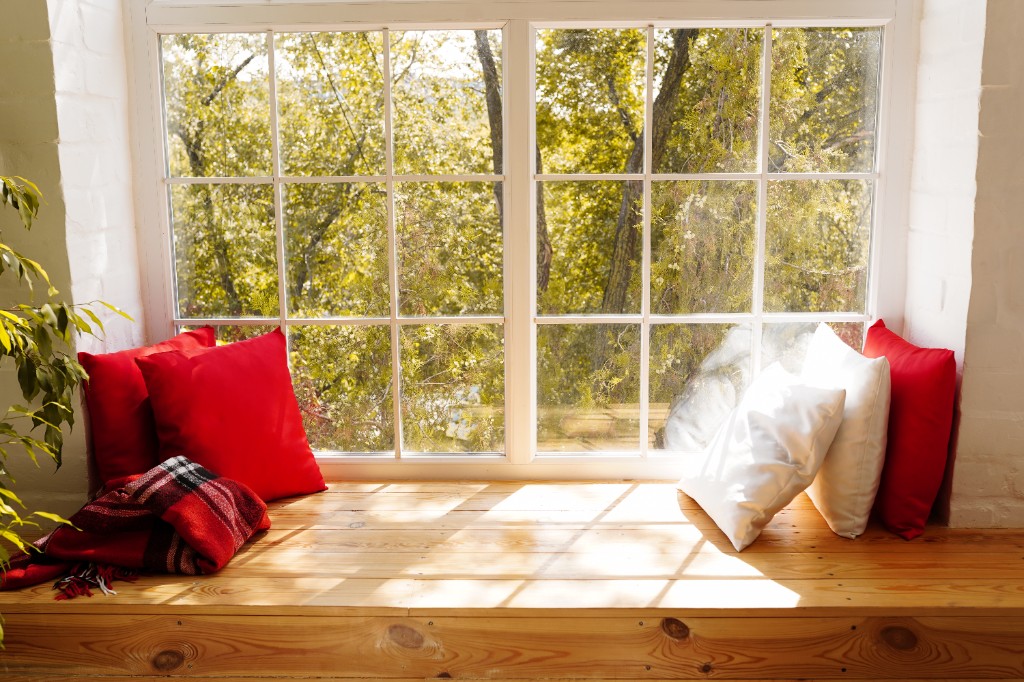 Large white-framed windows with a built-in bench seat and garden view